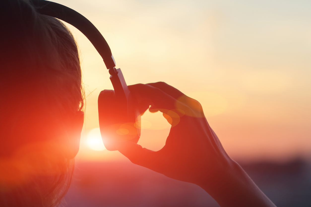 Girl in headphones listening to music in the city at sunset